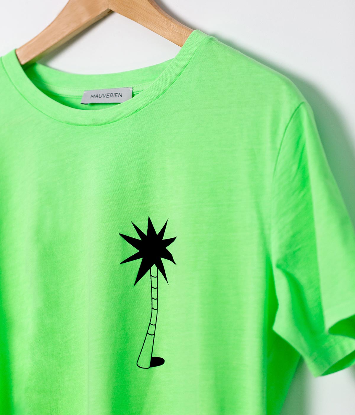 Close-up of neon green t-shirt with black palm tree print by Romanian designer Mauverien.
