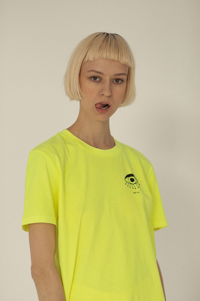 Woman wearing yellow cotton t-shirt with black eye print by Romanian designer.