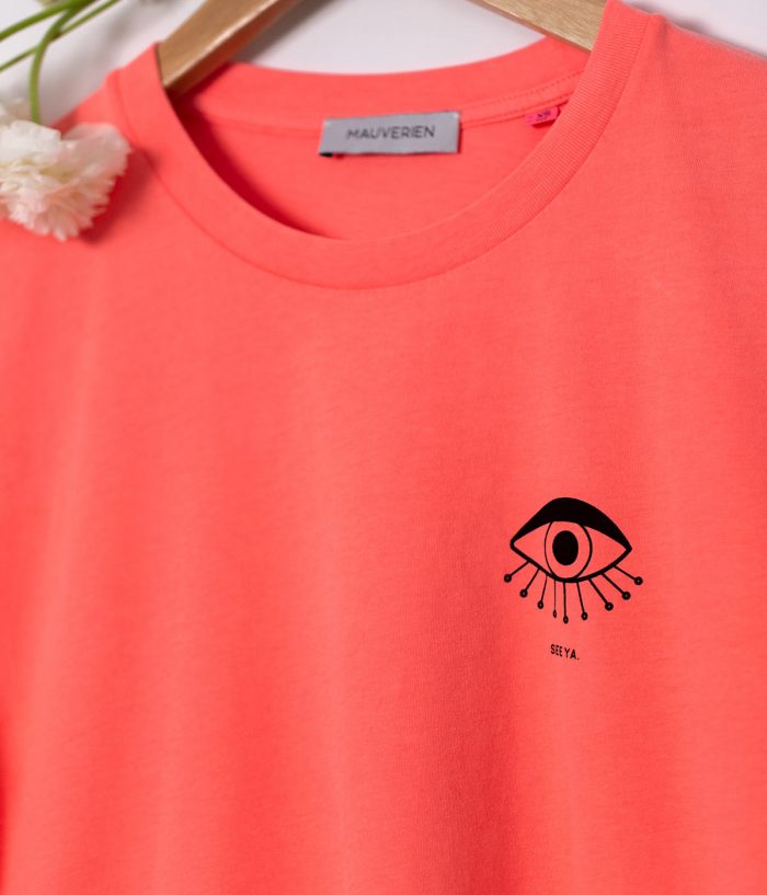Close-up of neon pink t-shirt with black print of a minimalist eye.