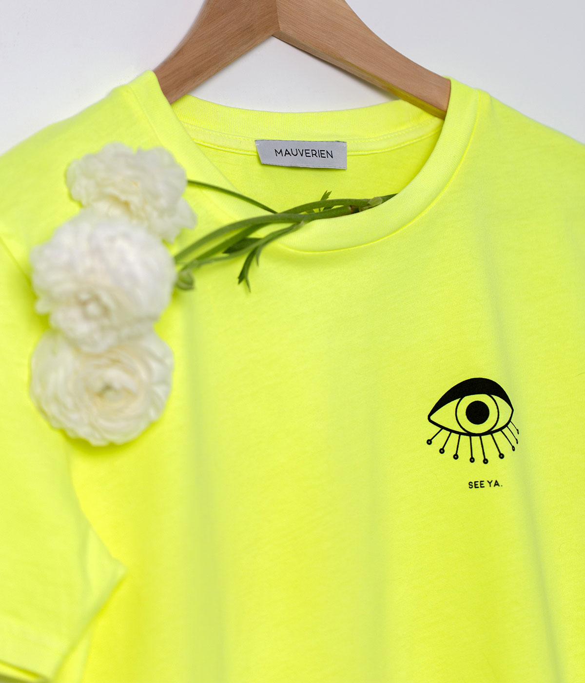 Detail of neon yellow t-shirt with black print of an eye and see ya message.