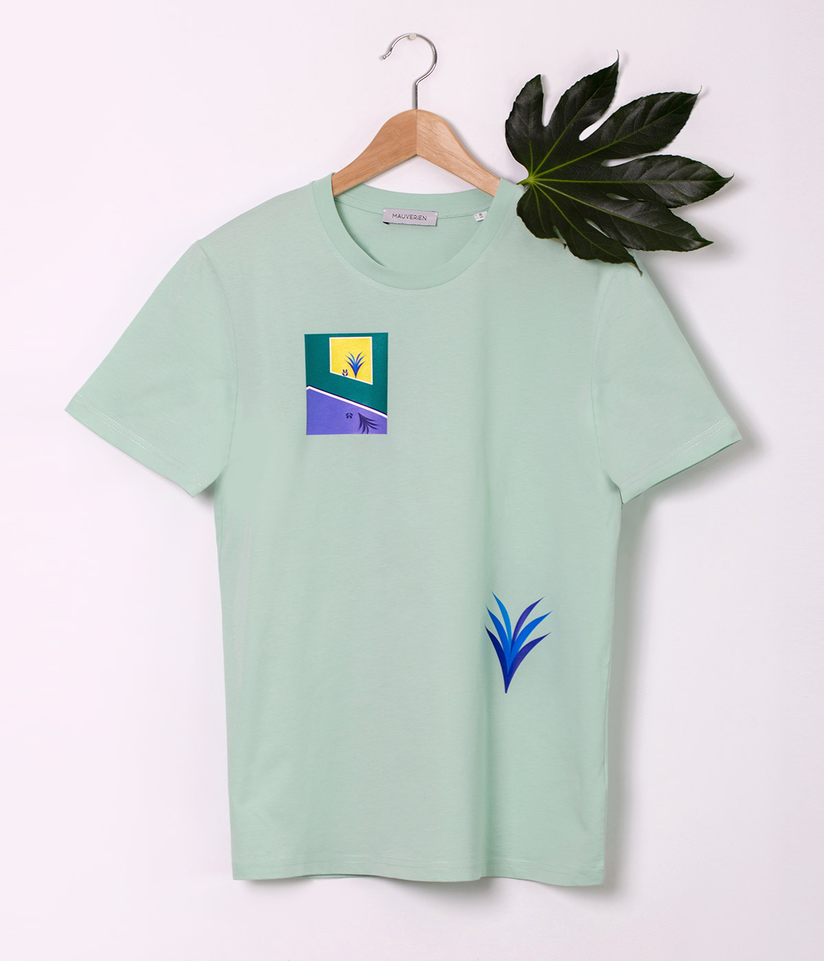 Fata unui tricou verde menta imprimat cu plante colorate in verde, mov si galben si pozitionate intr-un dreptunghi.