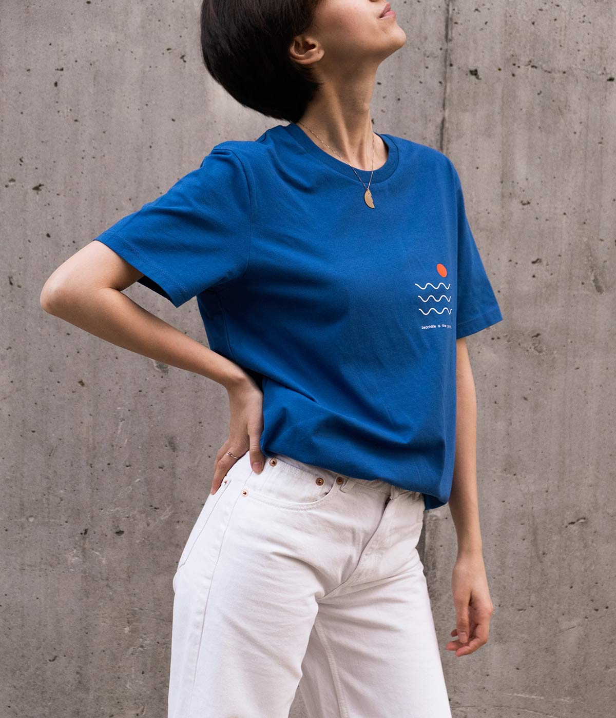 Fata cu tricou albastru imprimat cu print minimalist si blugi albi.