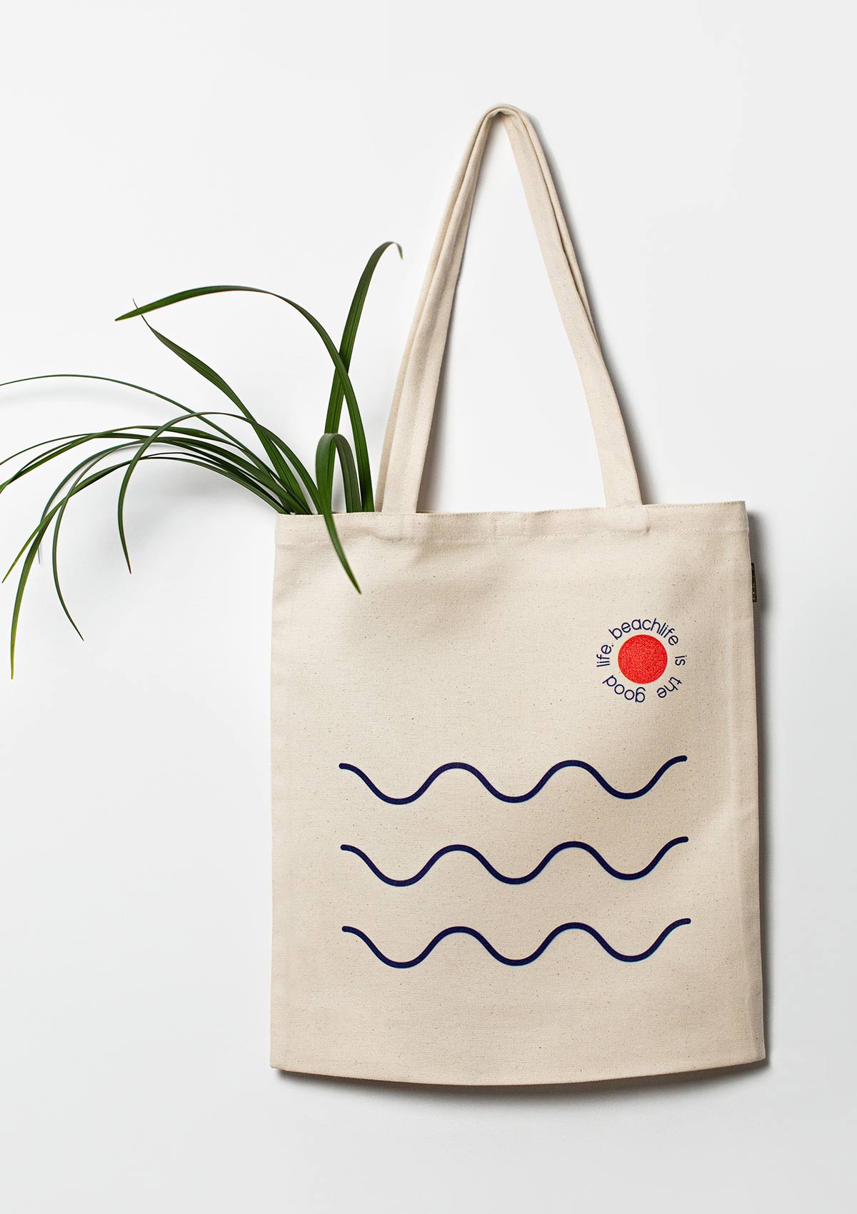 Beige cotton tote bag with three wavy bluemarine lines placed horizontally and writing around a small orange circle.