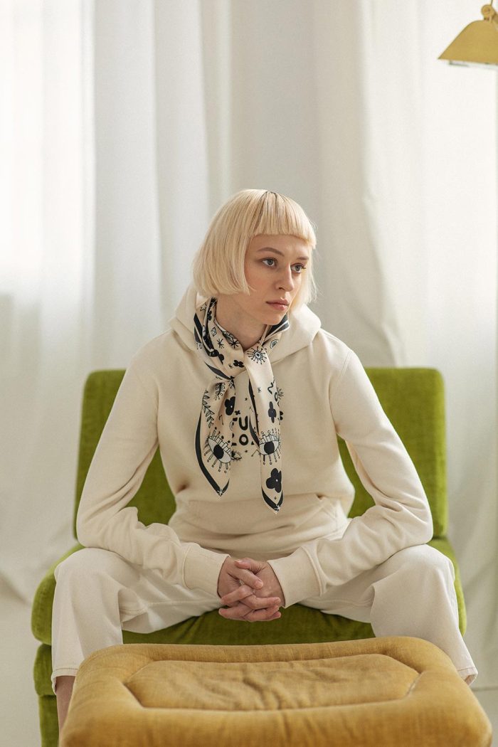 Blonde woman wearing beige neck scarf & beige sweatshirt from Mauverien.