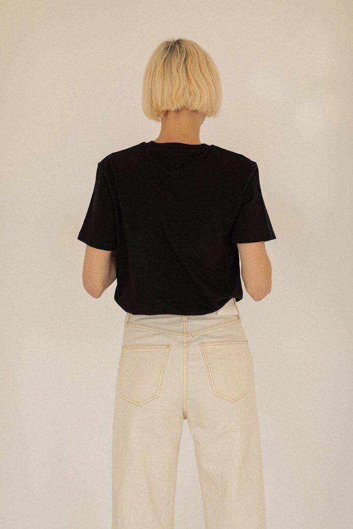 Back of woman wearing black t-shirt with crew neck and short sleeves.
