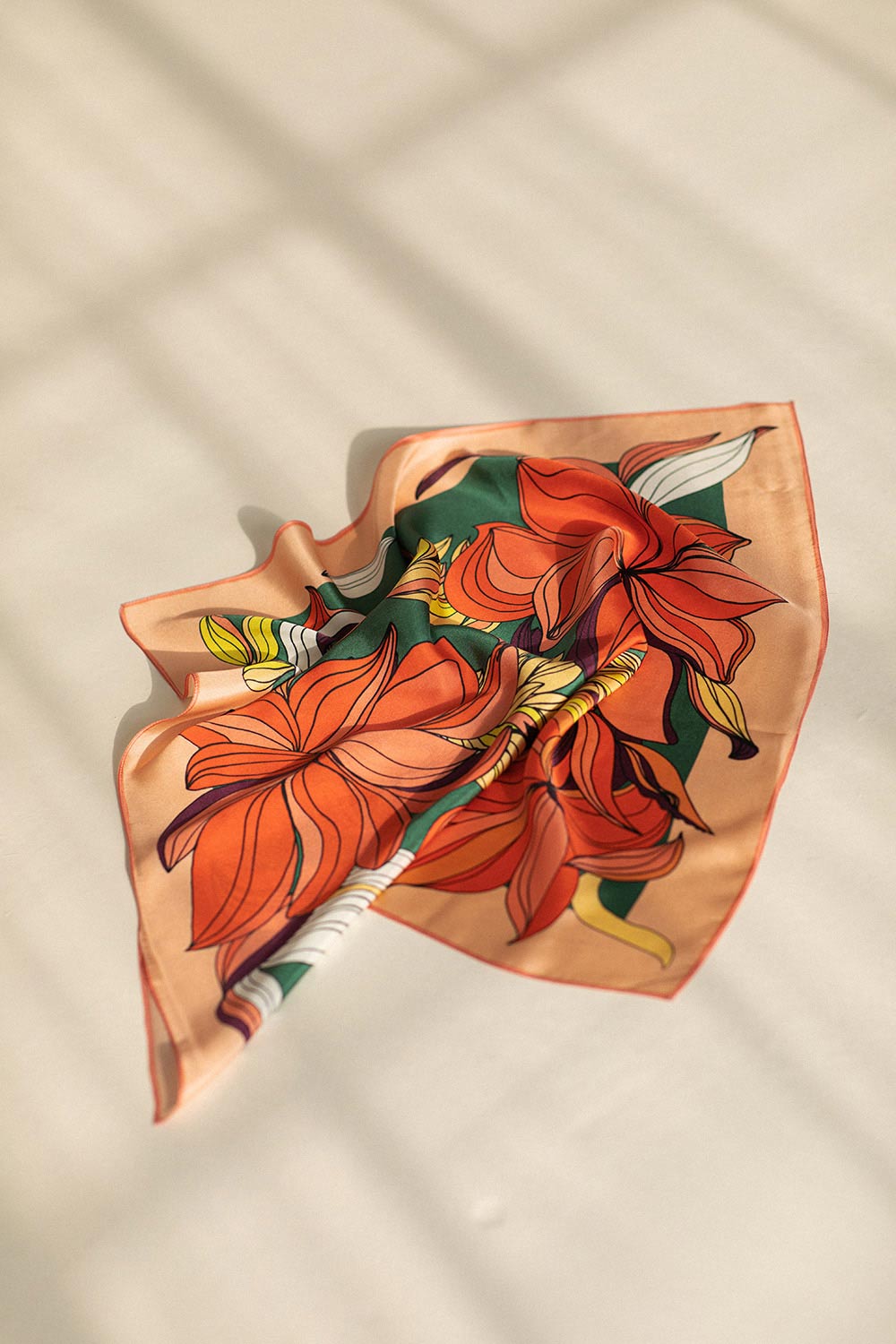 Folded red & green silk scarf with floral pattern & orange border created by Romanian designer Mauverien.
