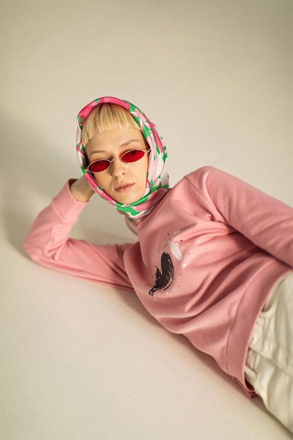 Woman wearing pastel pink and green floral head scarf and pink sweatshirt by Mauverien.
