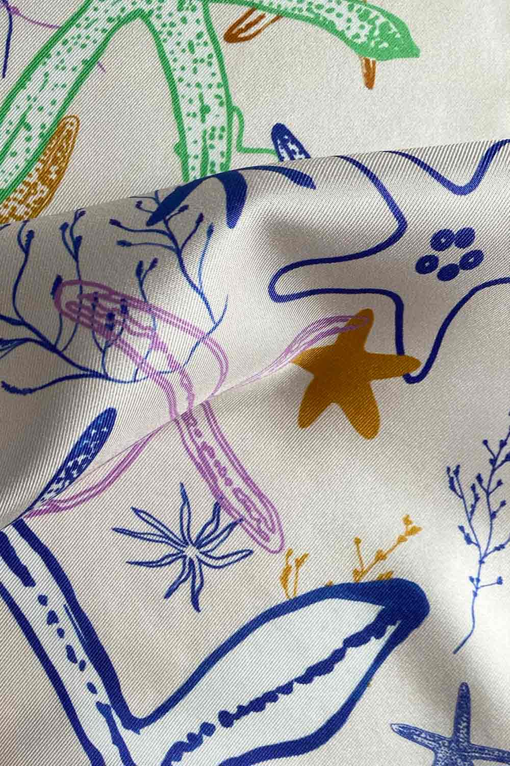 Detail of beige silk scarf with starfish illustration by Mauverien.