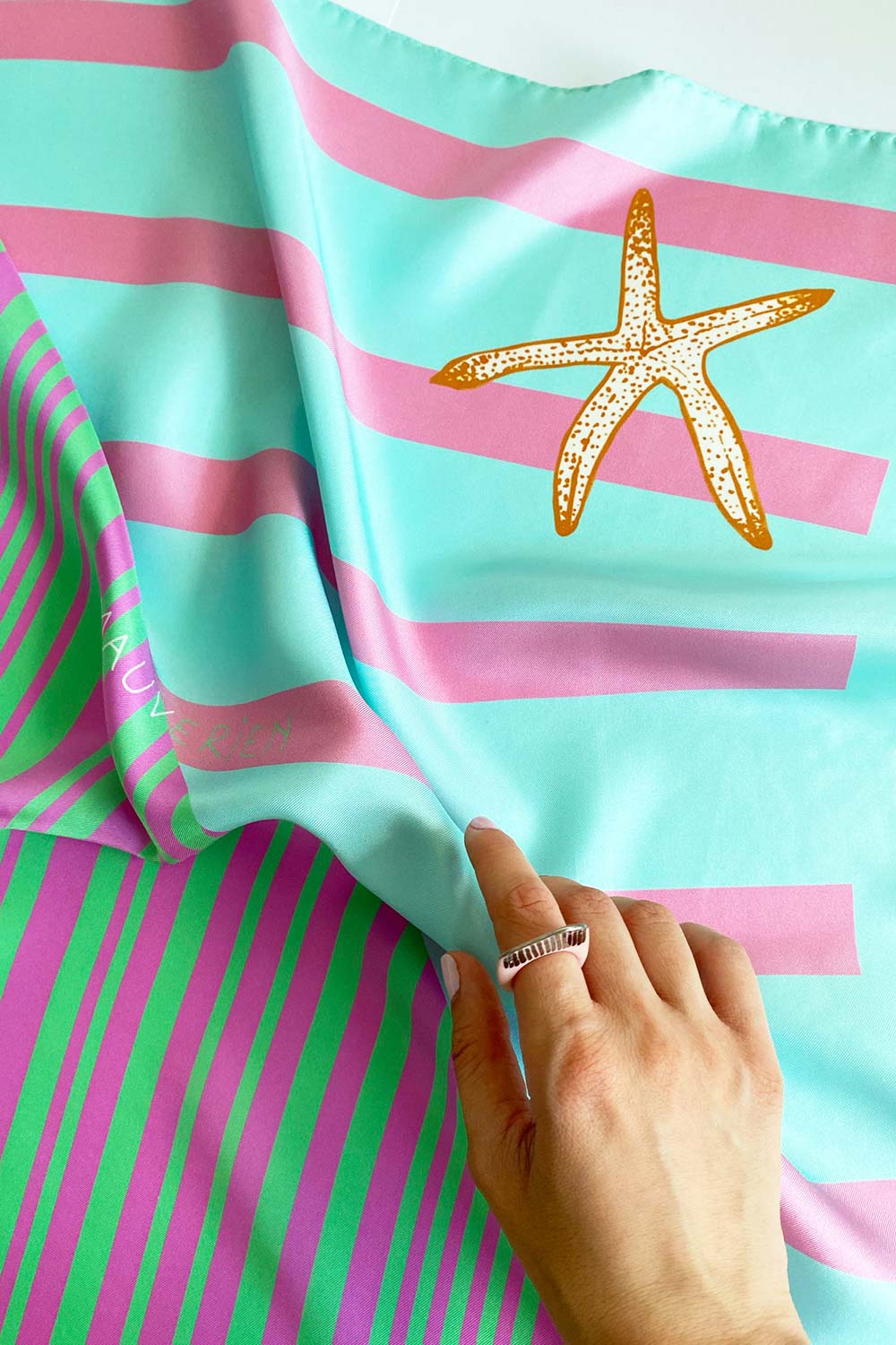 Detail of pink and green striped scarf with starfish print by Mauverien.