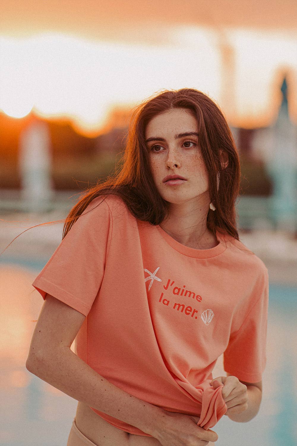 Woman wearing orange t-shirt La Mer with print by Romanian brand Mauverien.