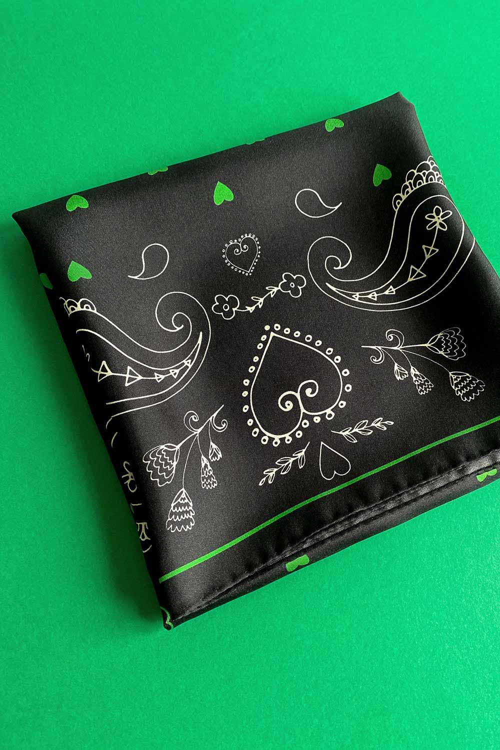 Folded black and green silk scarf with paisley pattern by Romanian designer Mauverien.