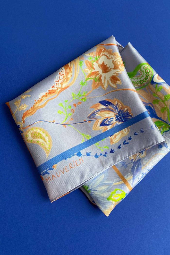 Folded blue silk scarf with orange floral pattern by Romanian designer Mauverien.