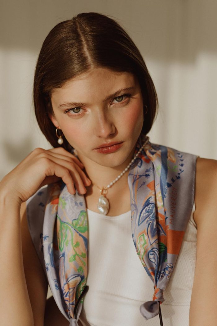 Woman wearing pearl necklace and blue floral silk scarf by Mauverien.