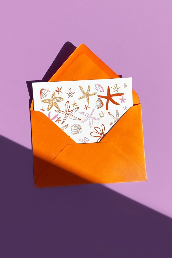 Greeting card illustrated with sea stars and shellfish in orange envelope.
