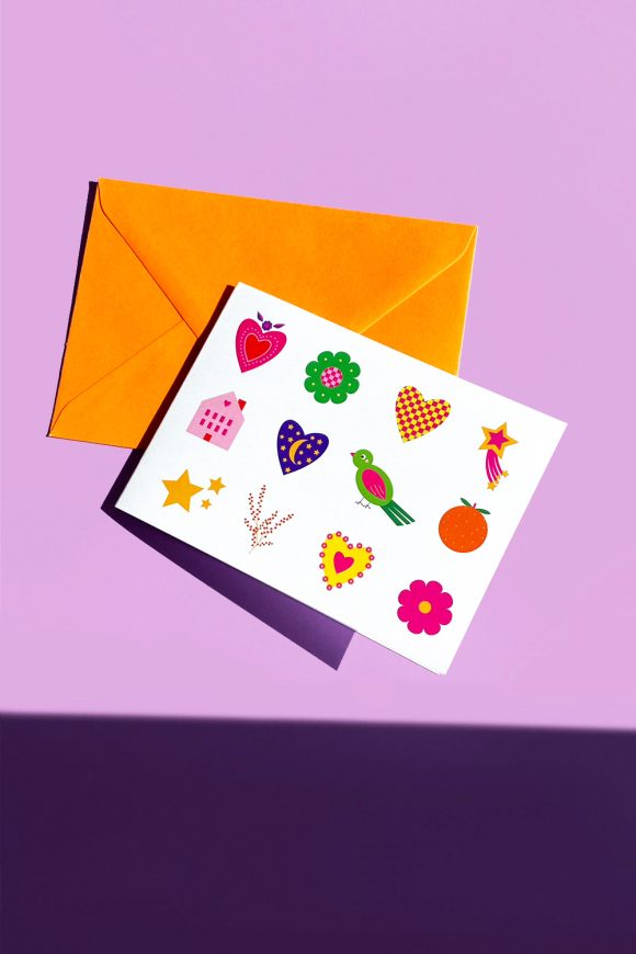 Greeting Card with Multicoloured Cookies Shapes and orange envelope.