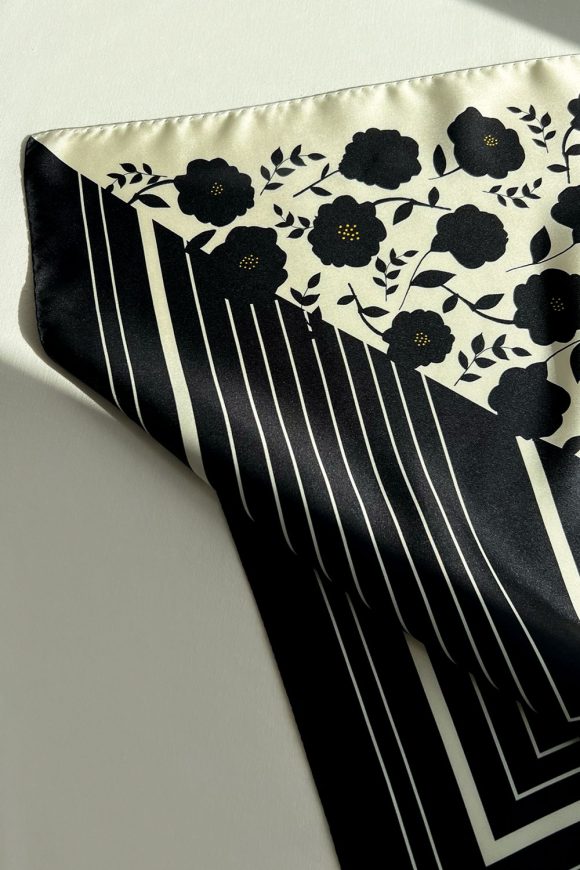 Black and white silk scarf with floral print and black stripes, corner detail.