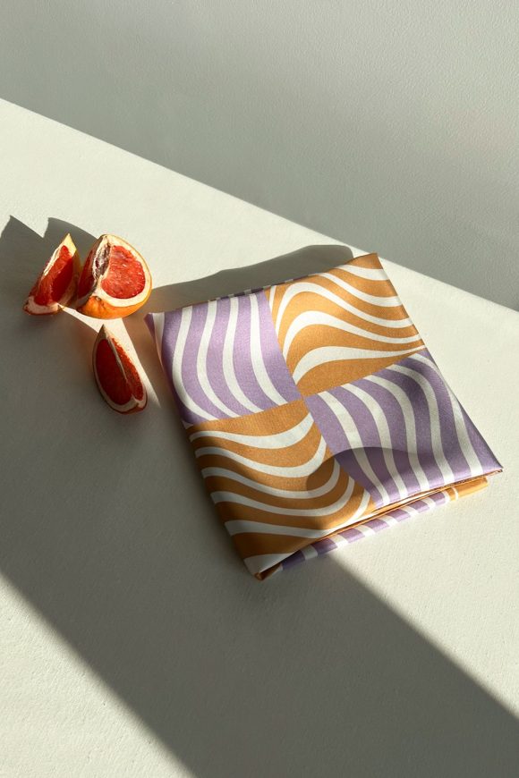 Folded silk scarf with wavy orange and purple pattern by Mauverien.